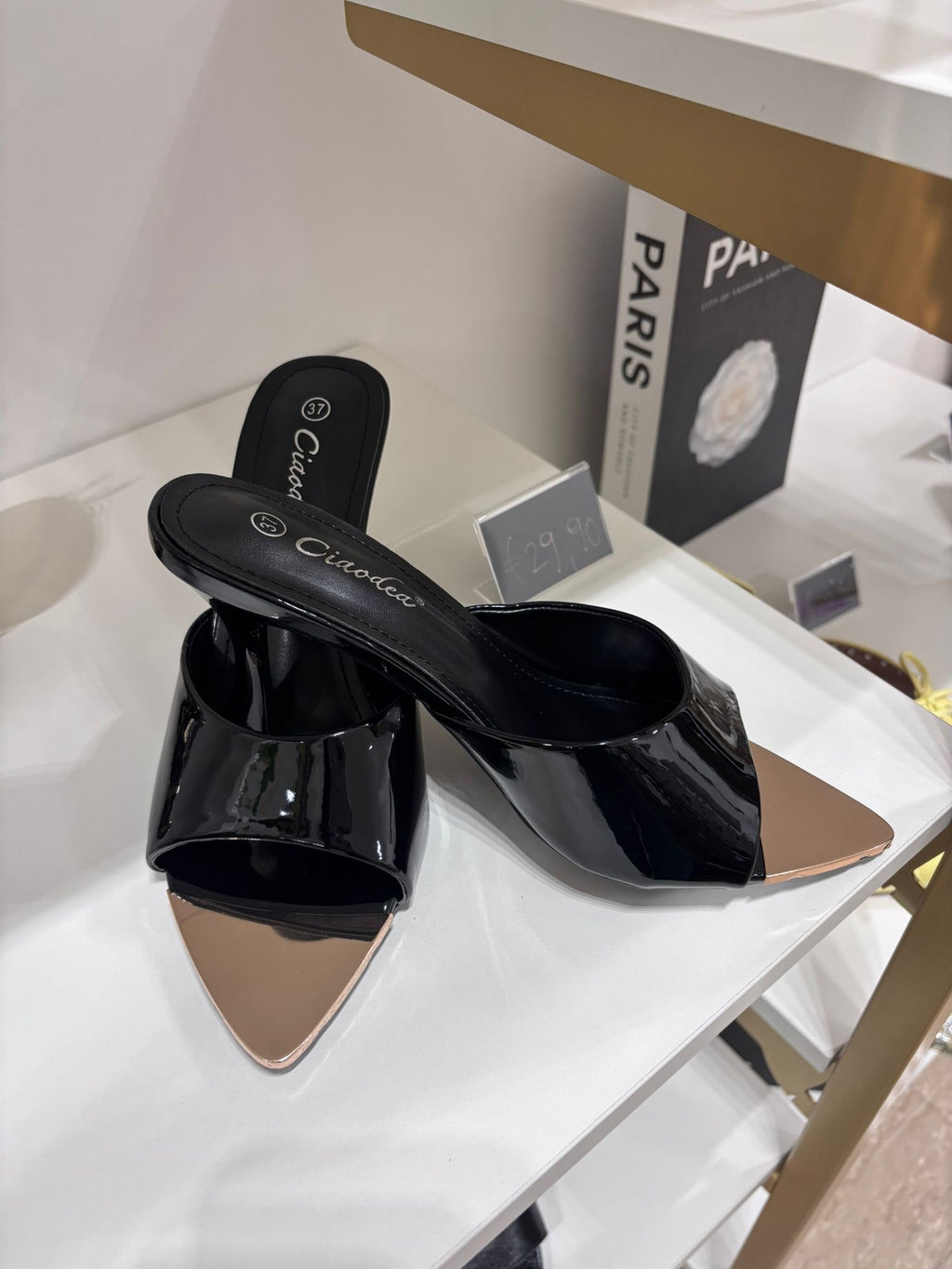 Black glossy patent leather mules with pointed beige toe and low block heel.