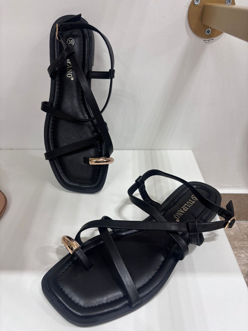 Black flat leather sandals with thin straps and gold ring detail on the front strap.