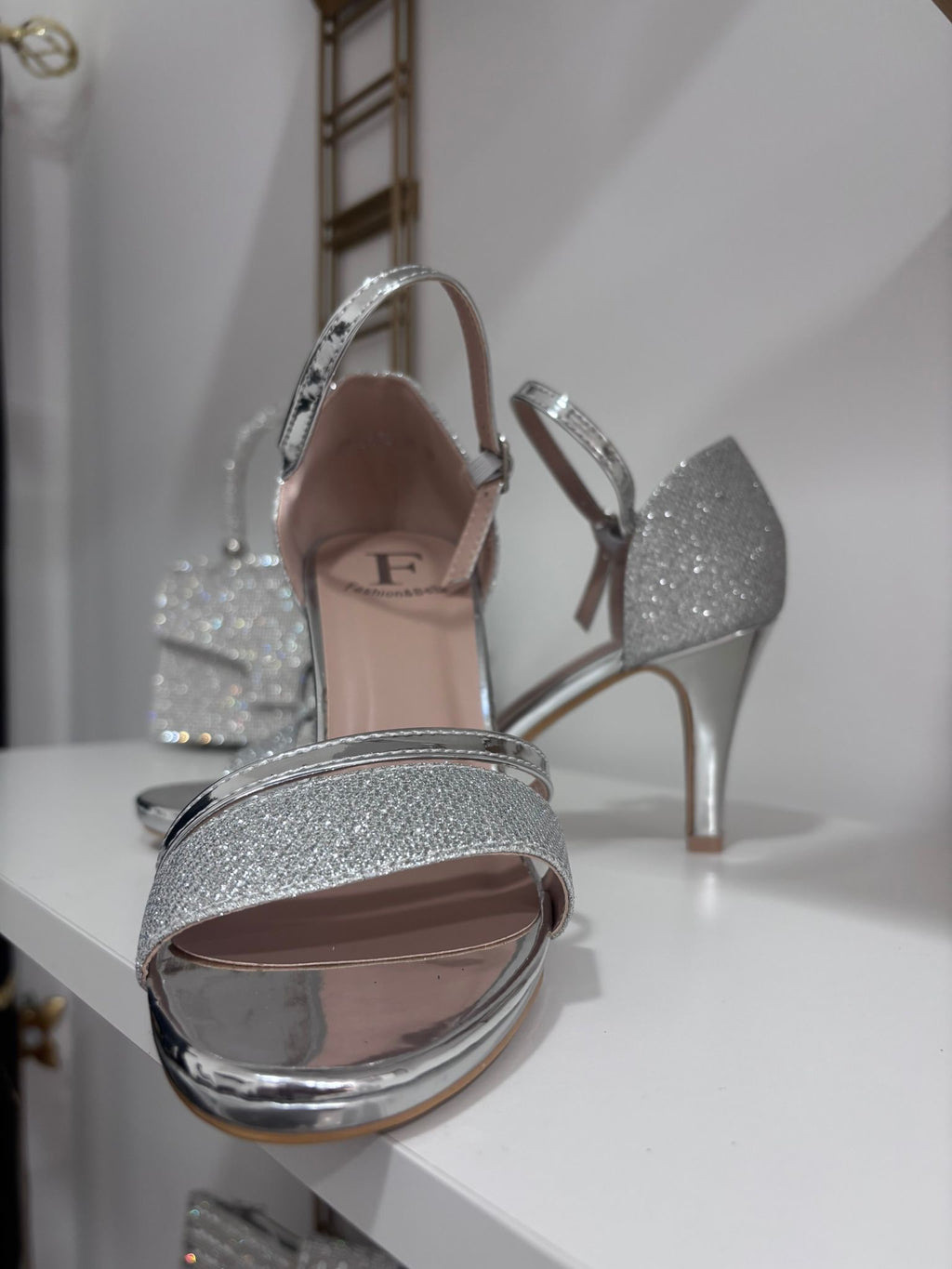 Silver glittery wedge sandals with square toe and slingback strap on white surface.