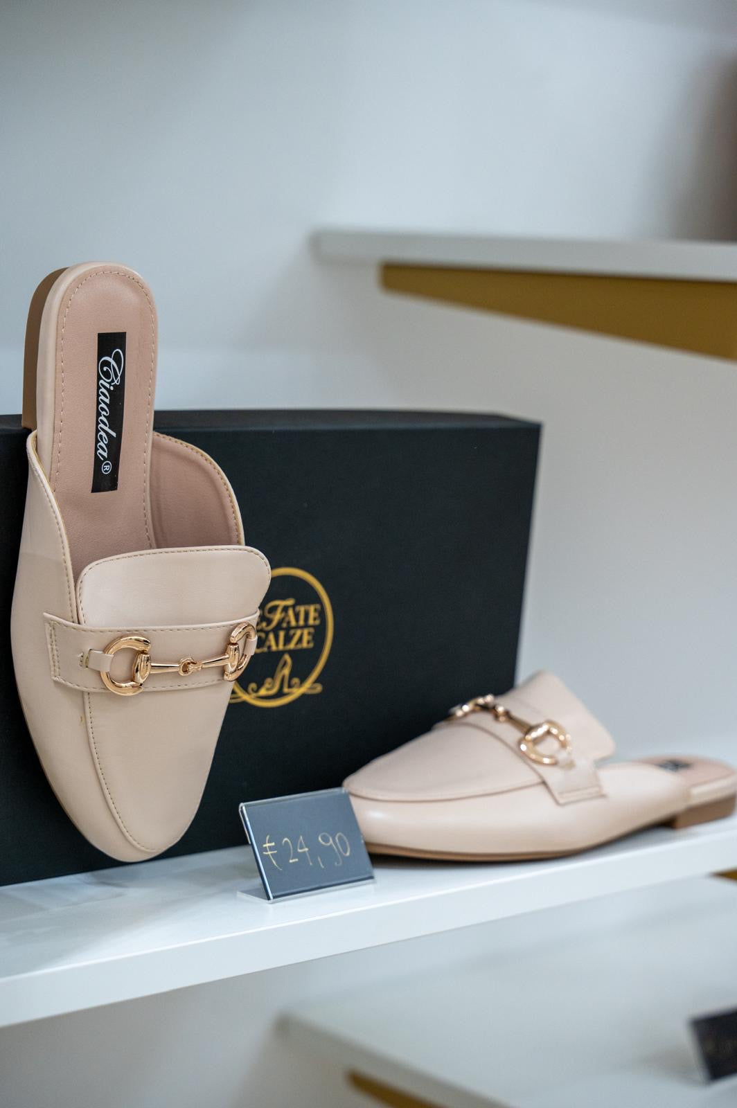 Beige open-back moccasin flats with gold chain detail on top, sleek minimalist design.