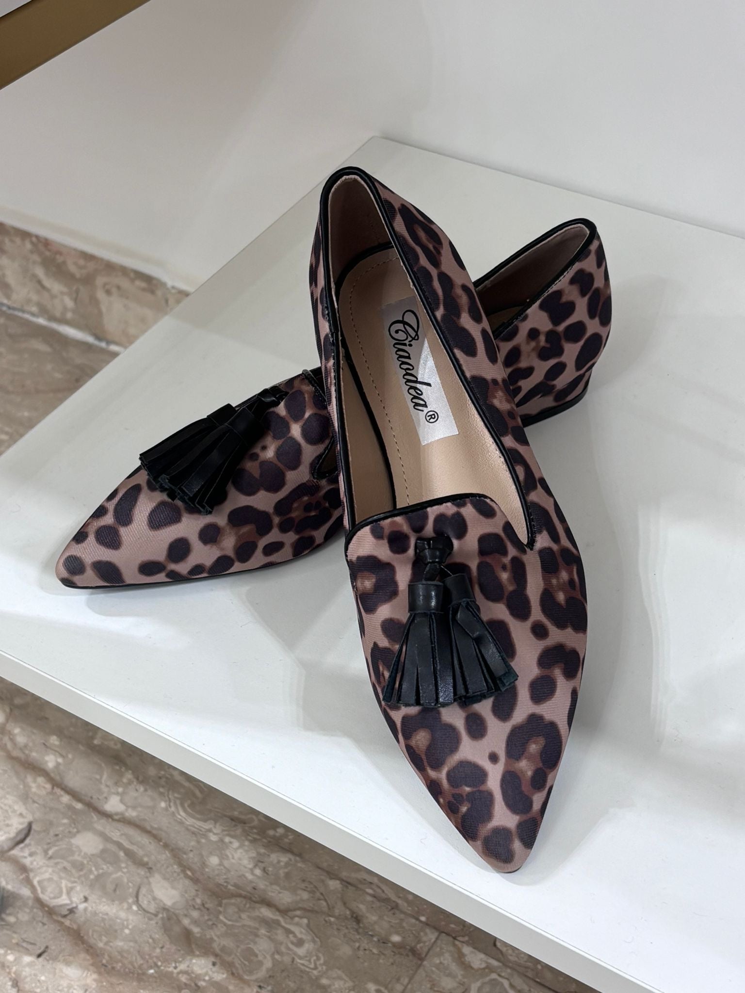 Pointed-toe women's loafers with brown and black tiger animal print and black tassel detail.