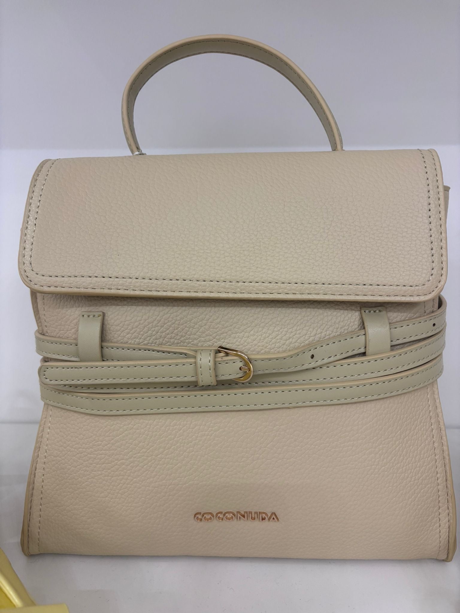 Cream leather backpack with flap closure, adjustable straps, and gold-tone buckle detail.