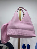 Pink perforated leather tote bag with two top handles and spacious interior.