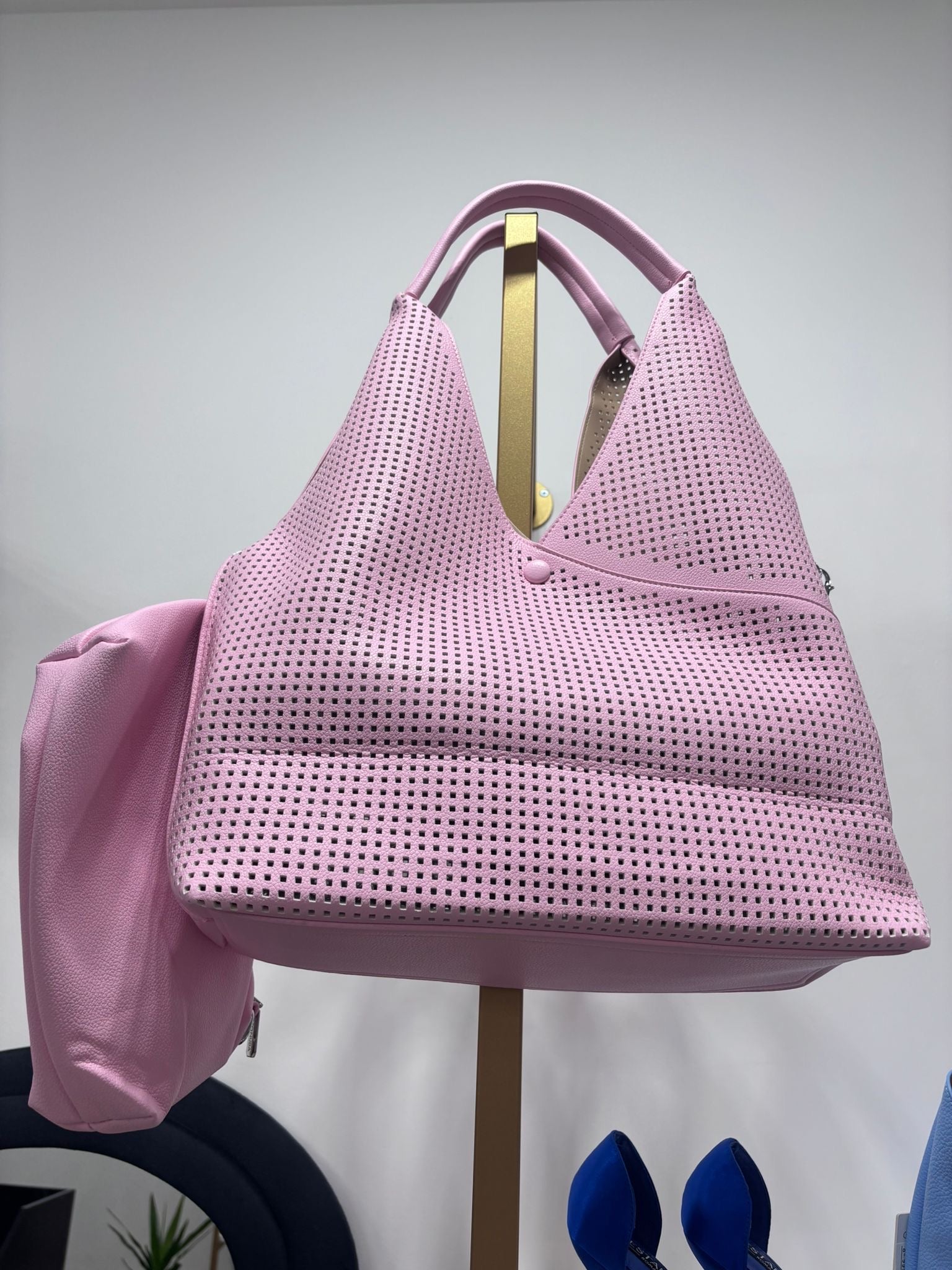 Pink perforated leather tote bag with two top handles and spacious interior.