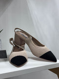 Beige crochet low-heeled sandals with black pointed toe and ankle strap.
