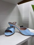 Light blue patent leather mules with open toe, block heel, and slip-on design on white surface.