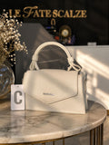 Cream leather mini lady bag with top handle and subtle gold logo detail on marble table.