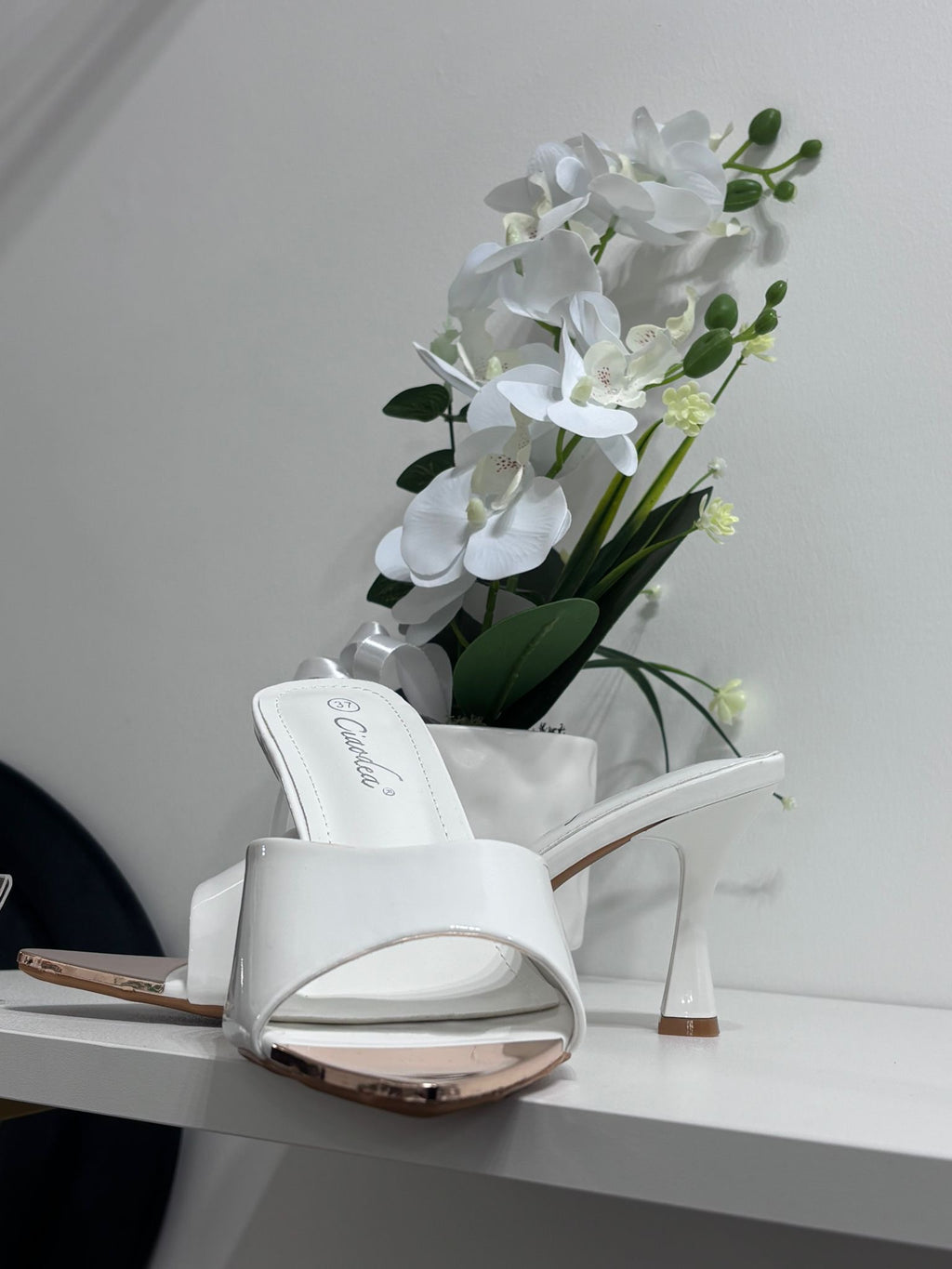 White glossy open-toe mule sandal with mid-height heel and slip-on design.