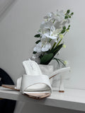 White glossy open-toe mule sandal with mid-height heel and slip-on design.