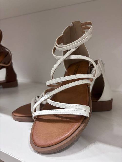 White leather flat sandal with multiple thin straps and ankle wrap detail.