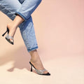 Black and silver glitter pointed mule heels with slim black stiletto, worn with rolled-up light blue jeans.