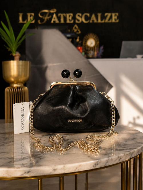 Black mini leather clutch with gold frame and chain strap, embellished with black bead clasp.