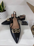 Black leather pointed-toe slingback flats with gold double-B embellishment and low block heel.