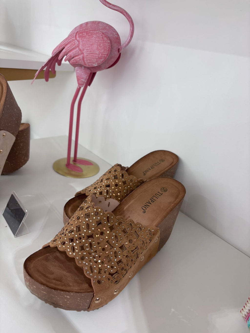 Beige suede wedge sandal with perforated floral design and wooden platform heel.