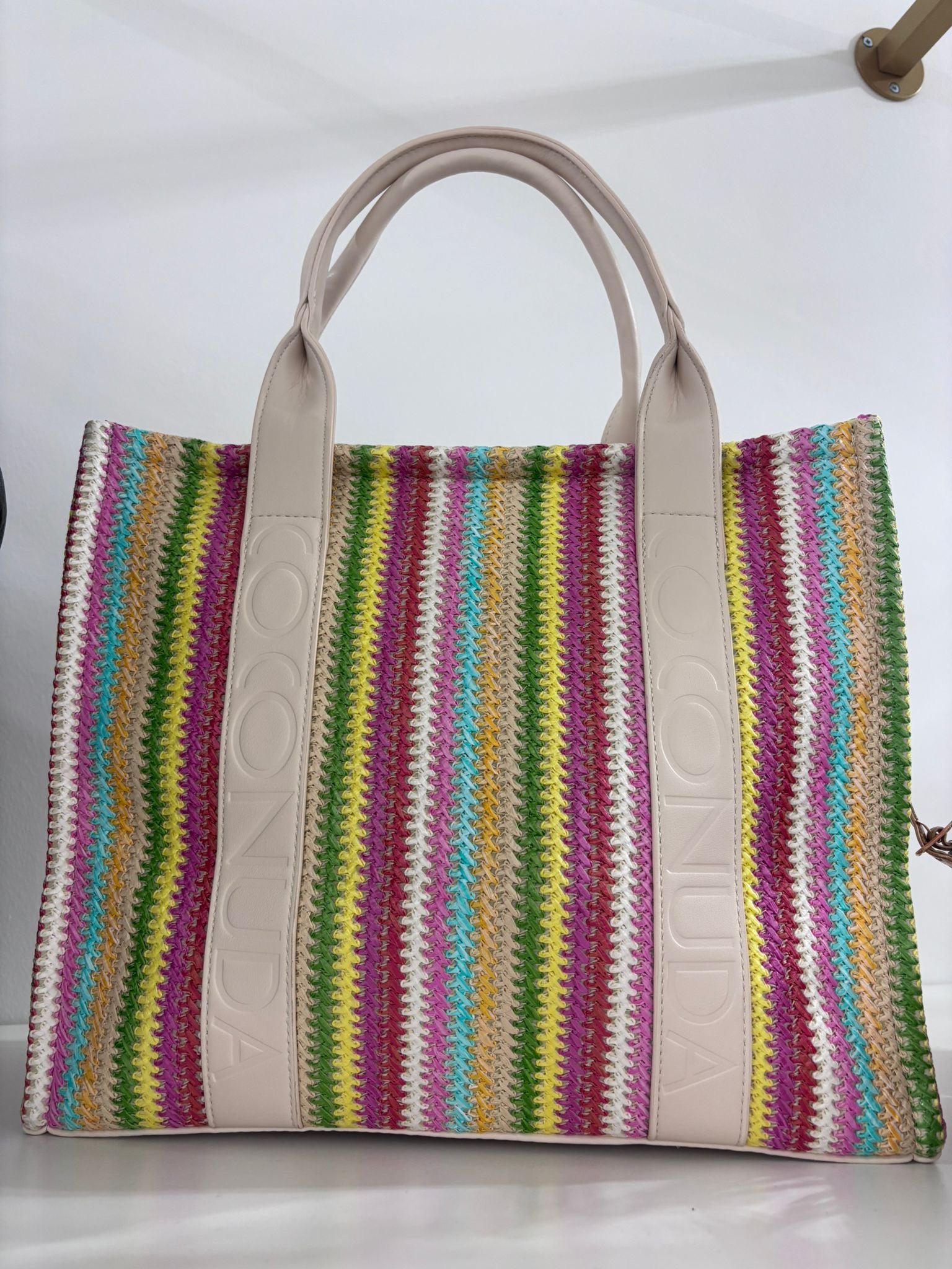 Multicolor striped woven tote bag with beige leather handles and trim.