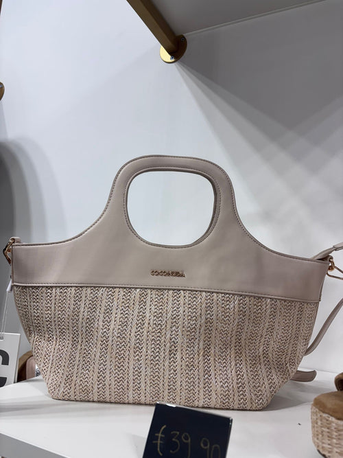 Beige structured tote bag with leather top, woven lower half, and cutout handles.