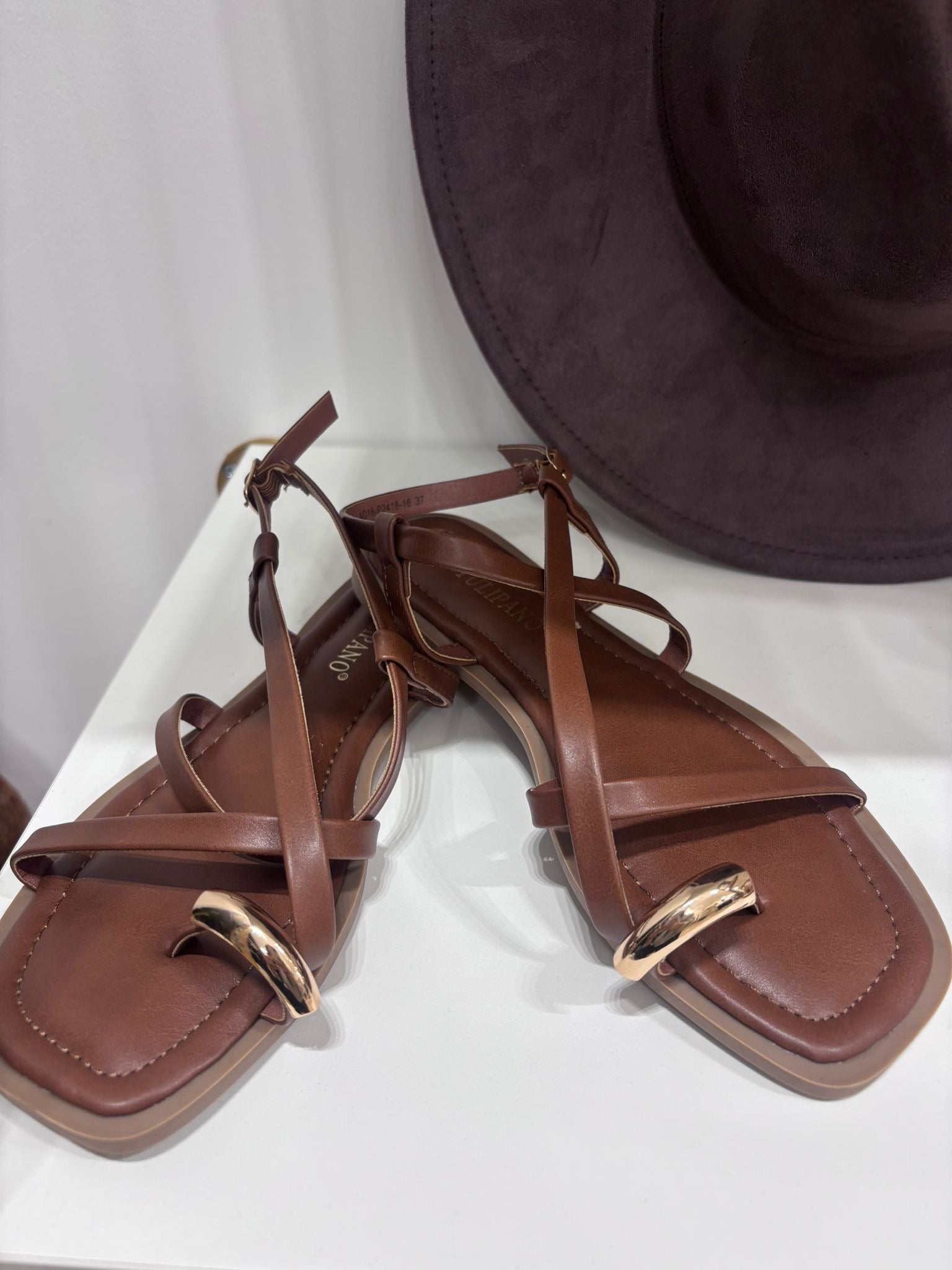 Brown leather flat sandals with ankle straps and gold ring detail, square toes.