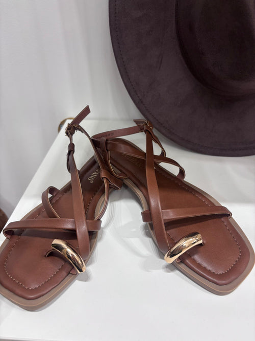 Brown leather flat sandals with ankle straps and gold ring detail, square toes.